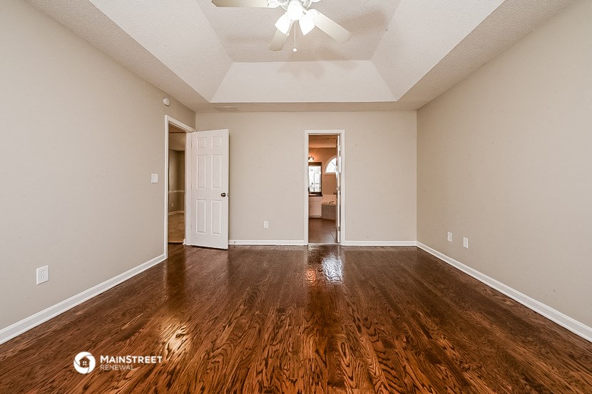 an empty living room with wood flooring and a ceiling fan