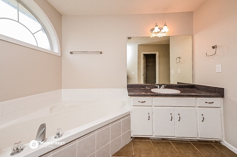 a bathroom with a tub and a sink and a mirror