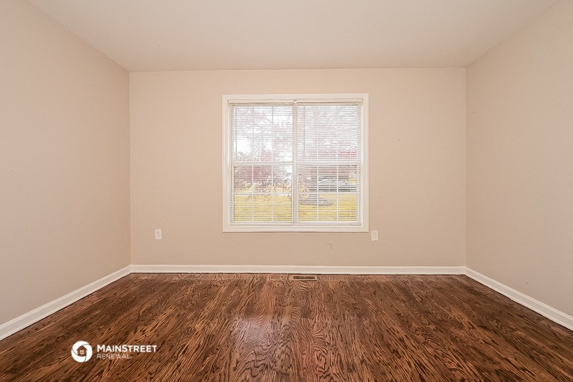 the living room of a home with wood floors and a window
