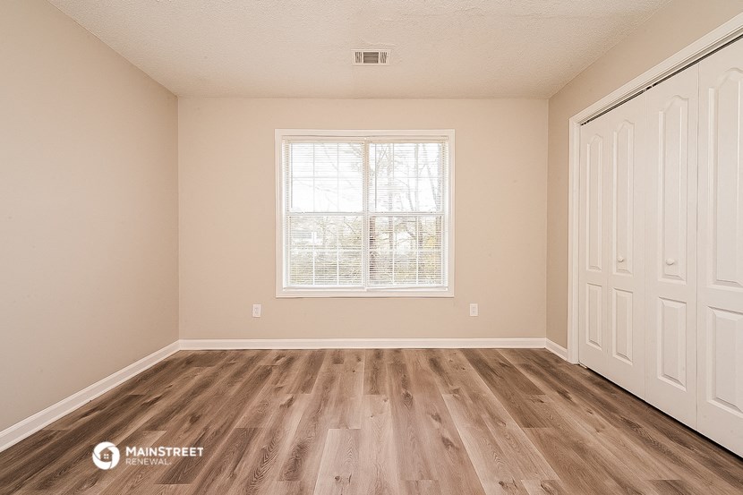 the spacious living room with wood flooring and a window