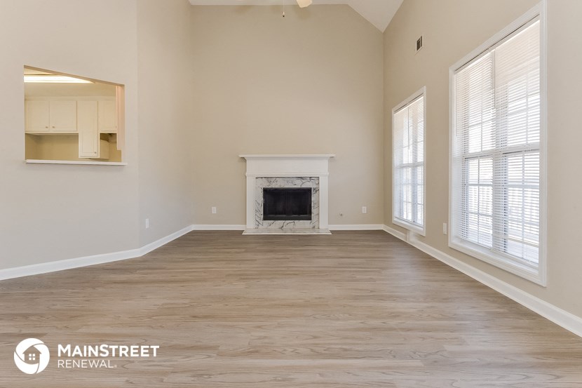 the spacious living room with a fireplace and large windows