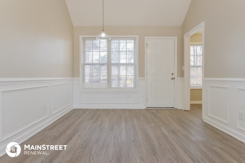 the living room of a home with white walls and wood floors