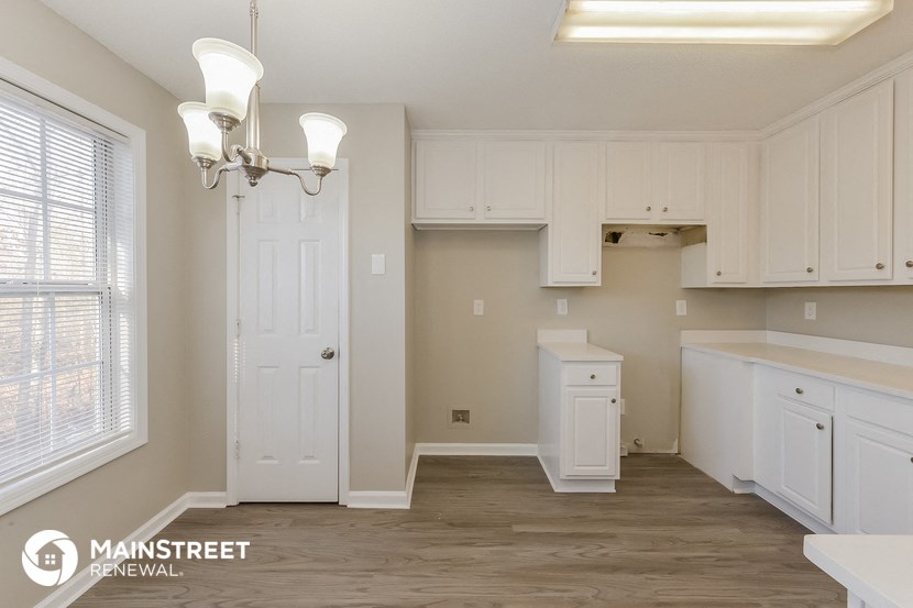 a kitchen with white cabinets and a large window