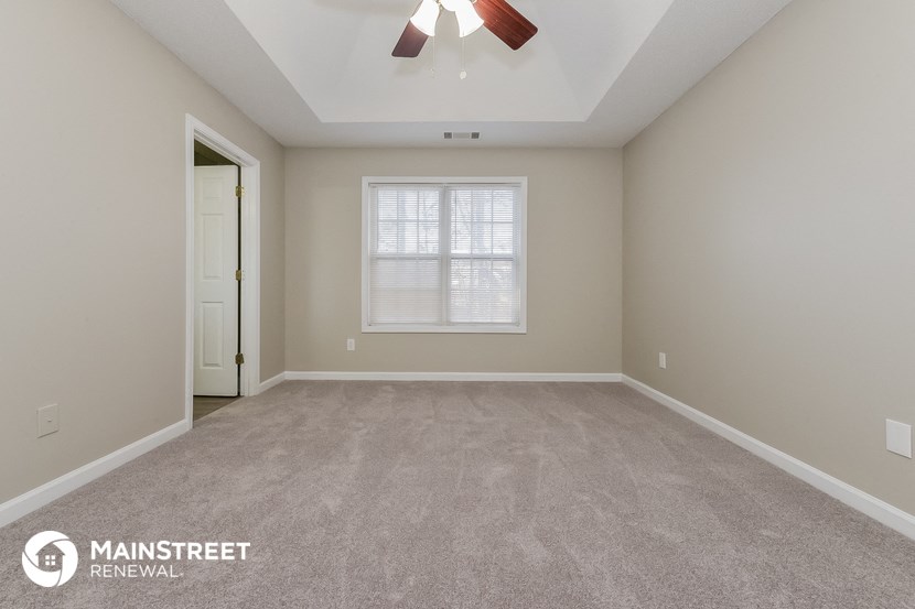 the spacious living room with carpeting and a ceiling fan