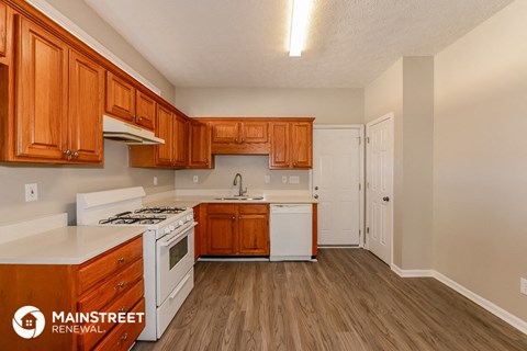 a kitchen with wood flooring and white appliances and wooden cabinets