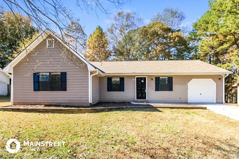 the front of a white house with a lawn and trees