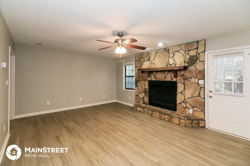 the living room has a stone fireplace and wood flooring
