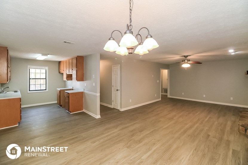 an empty living room and kitchen with wood flooring and a ceiling fan