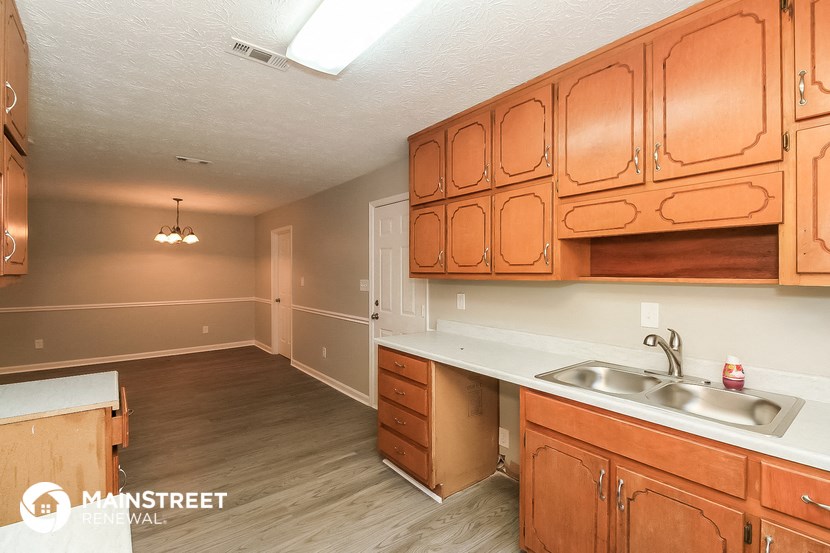 a kitchen and living room with wooden cabinets and a sink