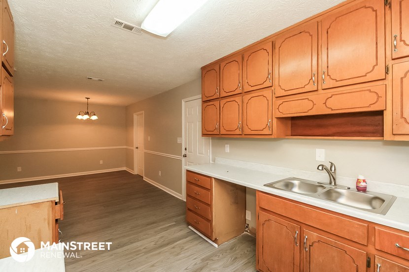 a kitchen and living room with wooden cabinets and a sink