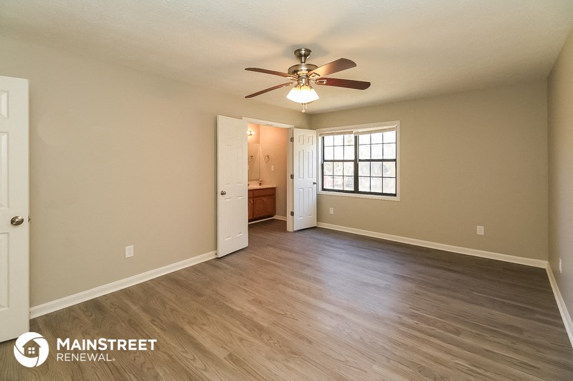 the spacious living room with wood flooring and ceiling fan