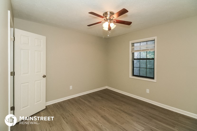 the interior of a bedroom with a ceiling fan and a window