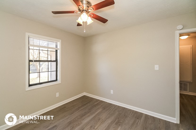 the spacious living room with a ceiling fan and a window