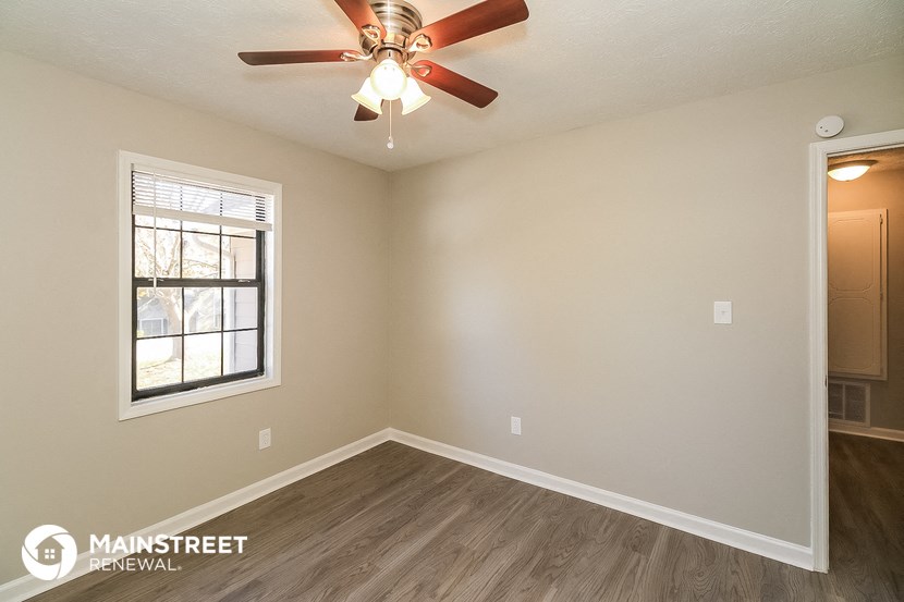 the spacious living room with a ceiling fan and a window