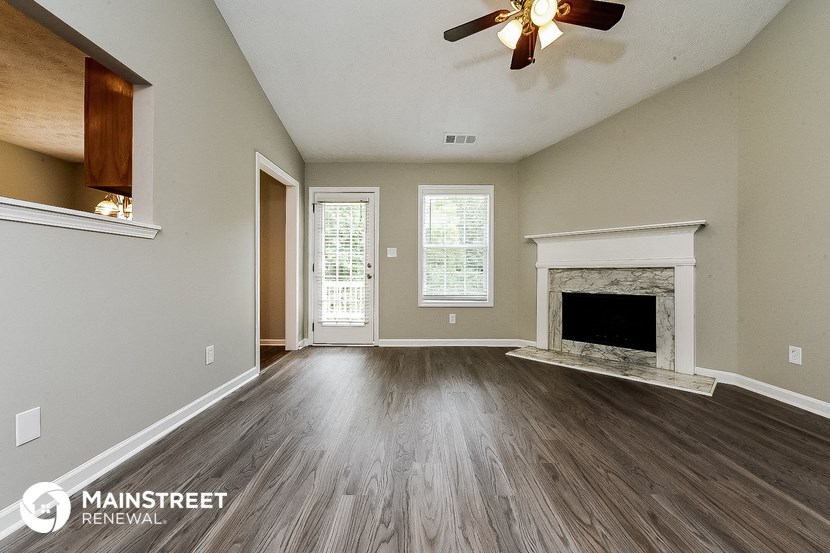 an empty living room with a fireplace and a ceiling fan