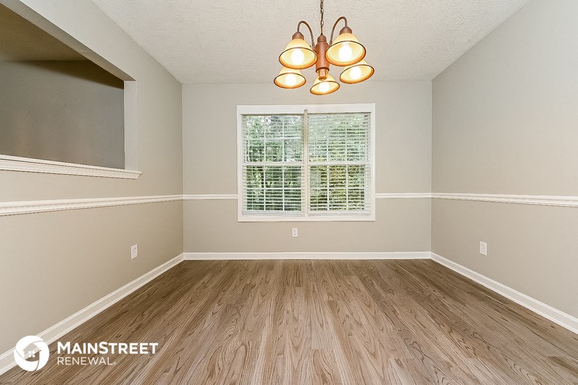 the living room of an empty home with wood floors and a window