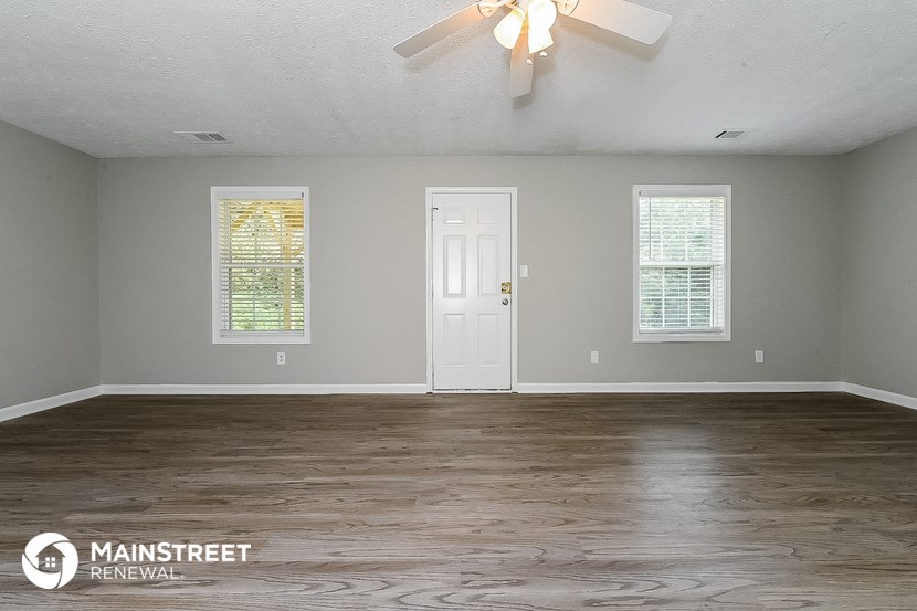 the living room of an empty house with a ceiling fan