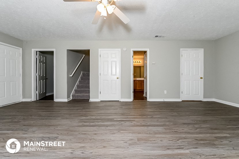 the living room of an empty house with white doors and a ceiling fan