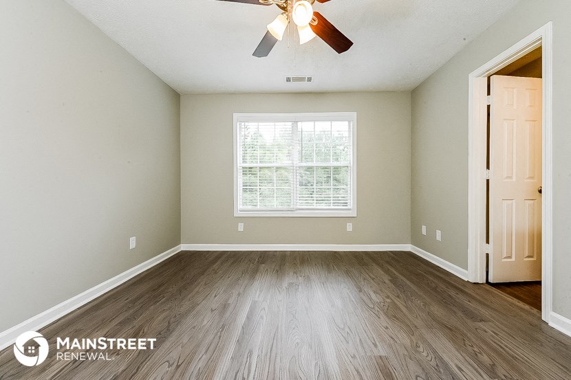 the master bedroom is spacious and has a ceiling fan and wood floors