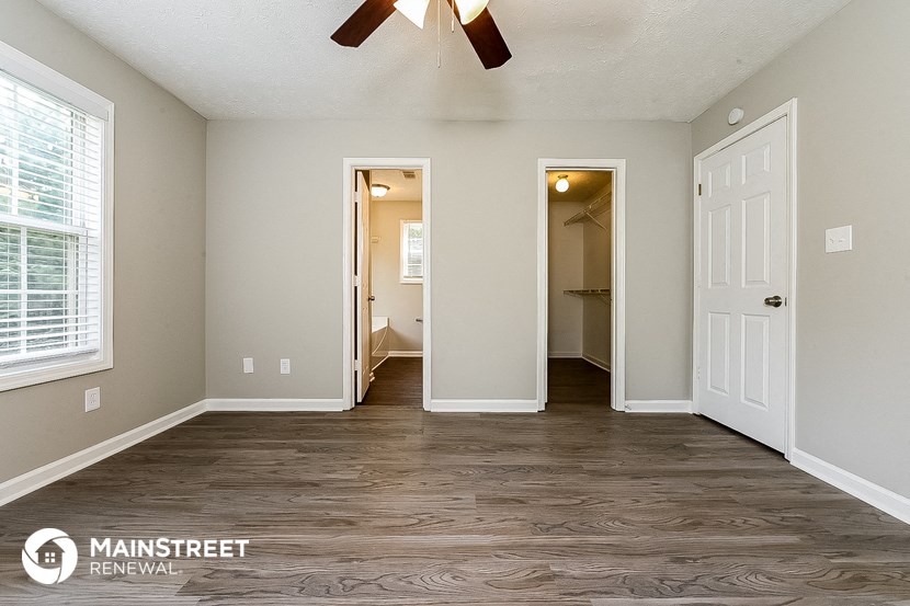 the master bedroom is spacious and has a large walk in closet and a ceiling fan