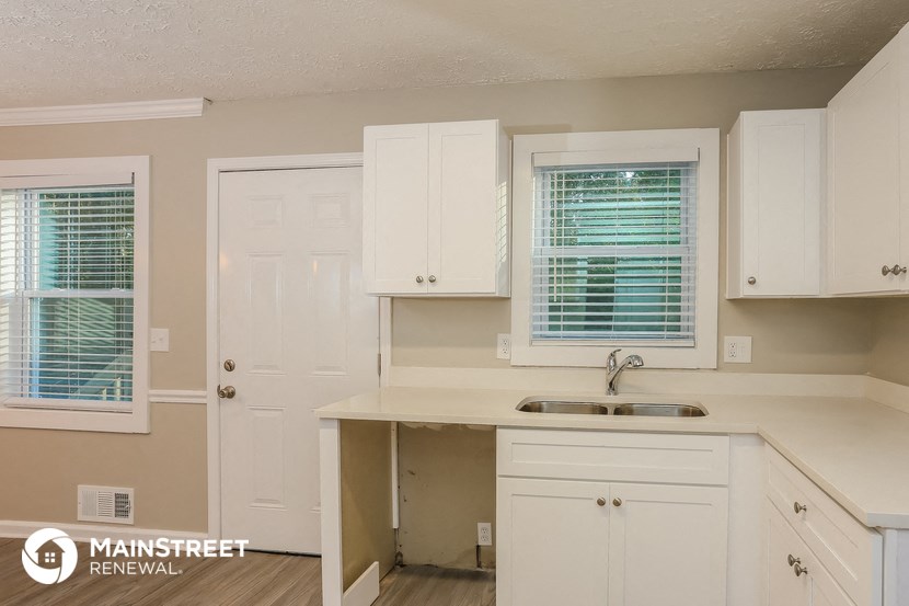 a kitchen with white cabinets and a sink and a window