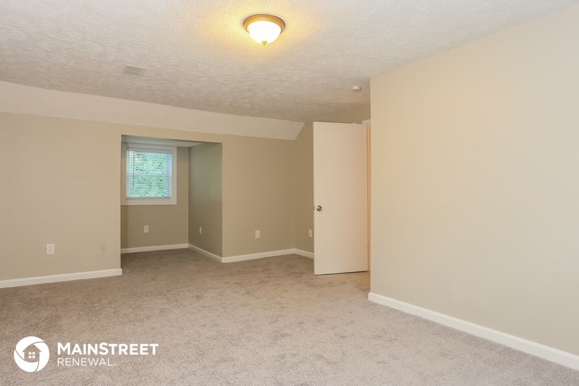 the spacious living room of this manufactured home has beige walls and white carpet
