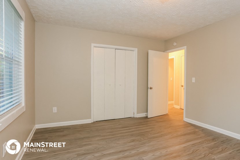 the living room of an apartment with wood floors and a white door