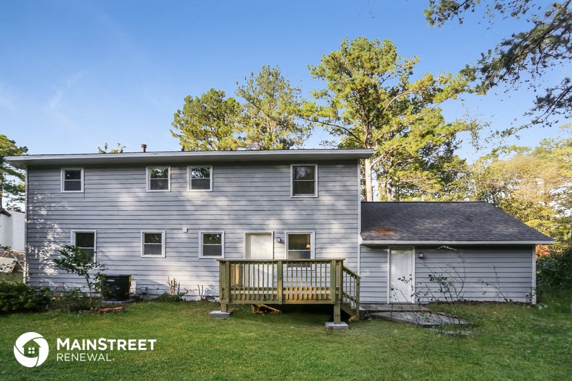 a backyard with a deck and a white house