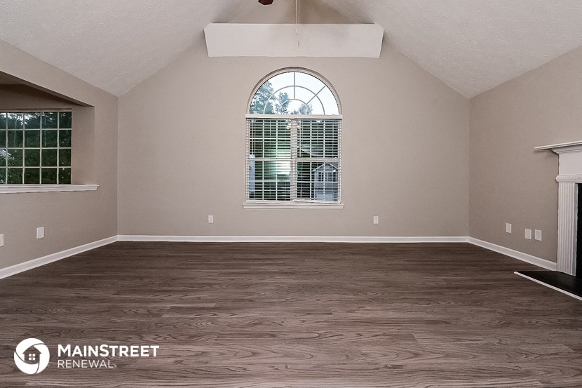 an empty living room with wood flooring and a large window