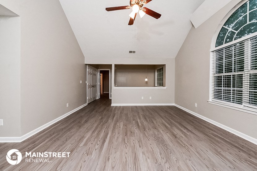 an empty living room with a ceiling fan and a window