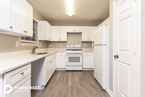 a white kitchen with white cabinets and a white stove and refrigerator