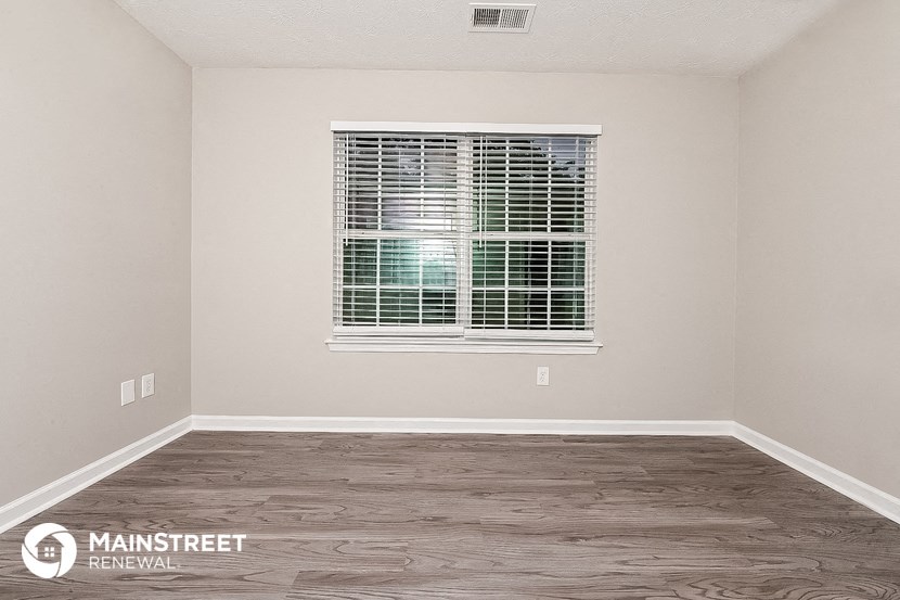 a bedroom with a window and a wood floor