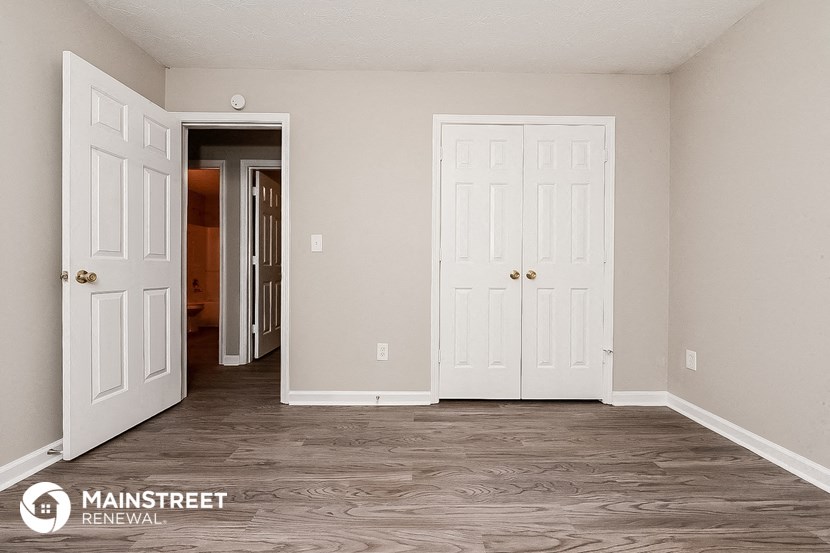 a bedroom with two doors and a door to a closet   and a hallway