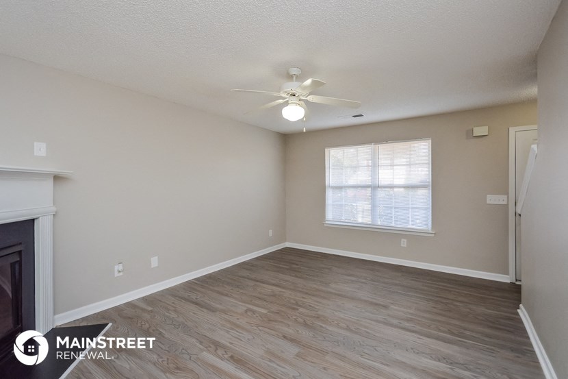 the spacious living room with wood flooring and a ceiling fan