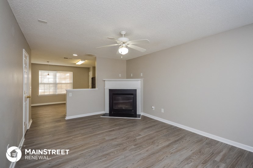 the spacious living room with fireplace and ceiling fan