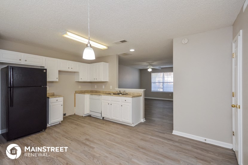 a kitchen with white cabinets and a black refrigerator