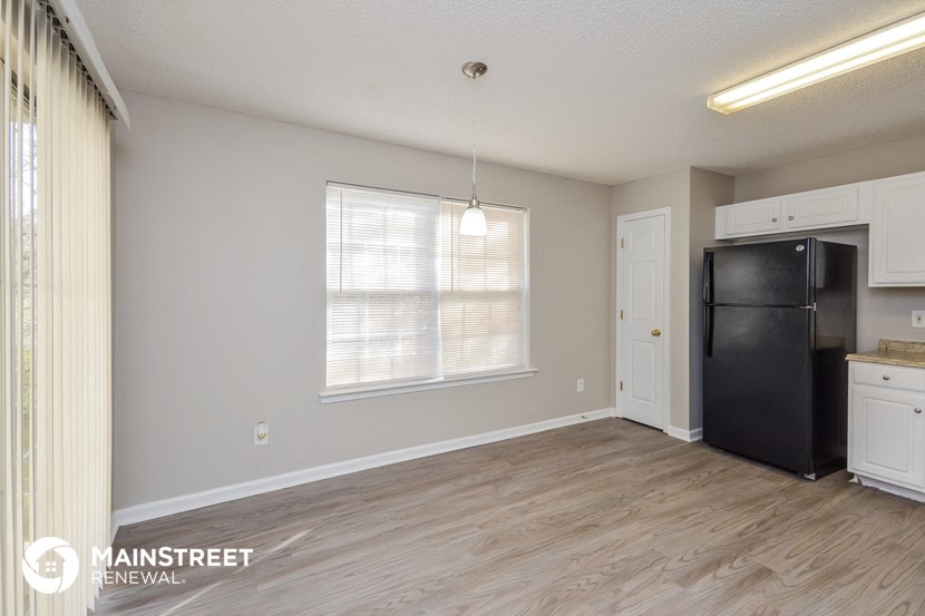 the kitchen and living room of an apartment with a refrigerator and a window