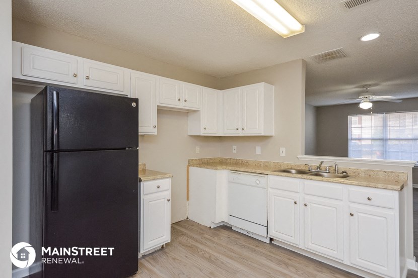 a kitchen with white cabinets and a black refrigerator
