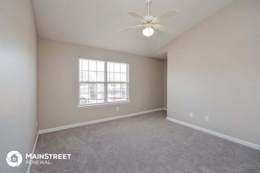 the spacious living room with carpeting and a ceiling fan