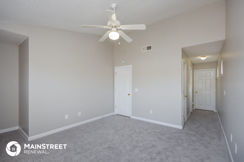 the spacious living room with ceiling fan and carpeting
