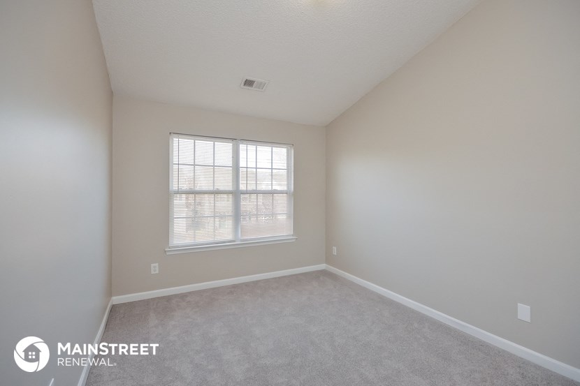 a bedroom with white walls and a window
