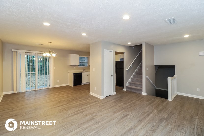 the living room and kitchen of a renovated house with wood flooring