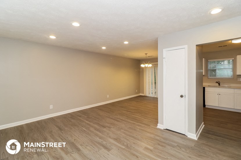 the living room and kitchen of a renovated house with wood flooring