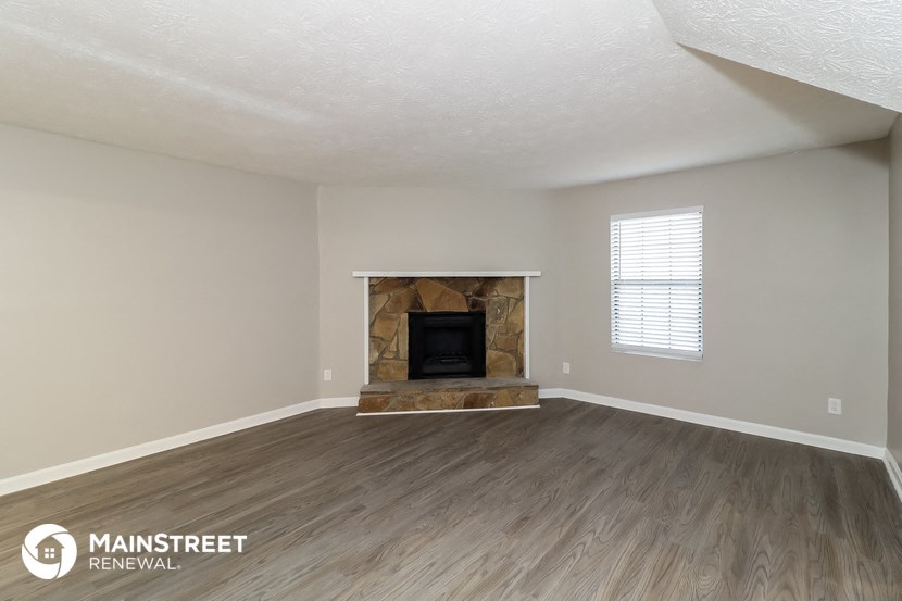 the living room of an apartment with wood floors and a fireplace
