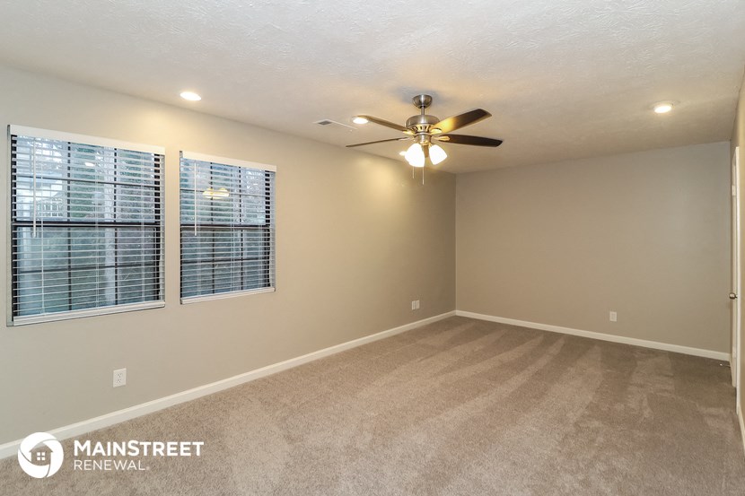 an empty living room with a ceiling fan and a window