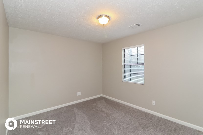 the spacious living room with carpeted flooring and a window