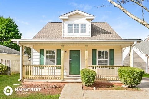 a small white house with green doors and a porch