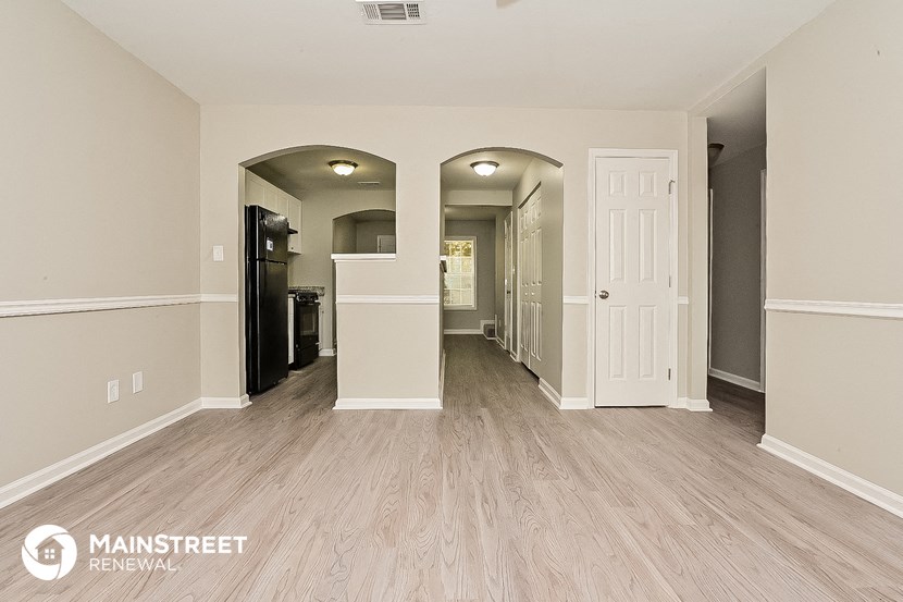 a spacious living room with wood flooring and a hallway to the kitchen