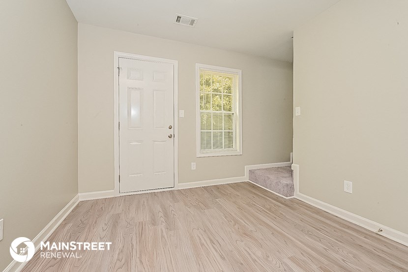 an empty room with a white door and wood flooring