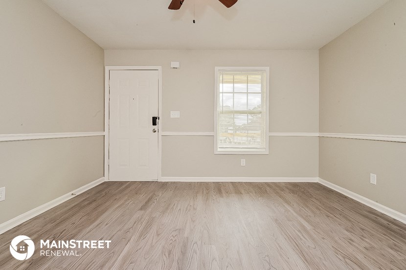the spacious living room with wood flooring and a white door